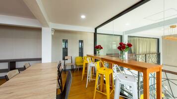 A modern meeting room with a wooden table, yellow and white chairs, and a glass partition.