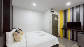 Habitación de hotel con cama, televisor, refrigerador pequeño y una puerta con un letrero.