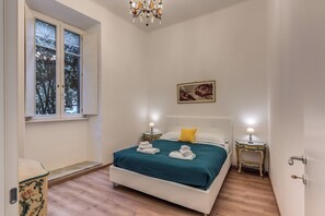 Ein Schlafzimmer mit einem Bett, zwei Nachttischen mit Lampen, einem Fenster und einem Bild an der Wand.