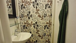 Ein kleines Badezimmer mit Toilette, Waschbecken und einer blumengemusterten Duschvorhang.