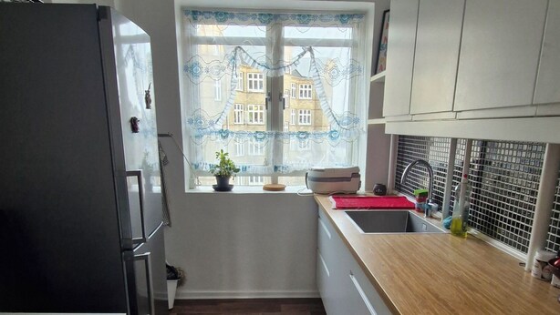 Eine moderne Küche mit Holzarbeitsplatte, eingebautem Backofen und einem Fenster mit Blick auf Gebäude.