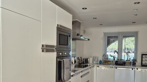 Une cuisine moderne avec des meubles blancs, des appareils électroménagers en acier inoxydable et un plancher en bois.