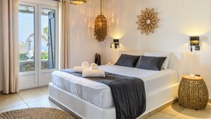 Camera da letto con un letto, un'ampia finestra, una lampada a sospensione e un elemento decorativo al muro.