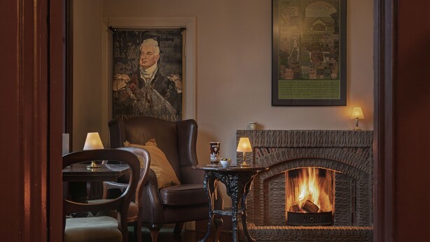 A cozy room with a fireplace, leather armchair, and a table with a lamp. - King William Pub with Rooms (Bath)