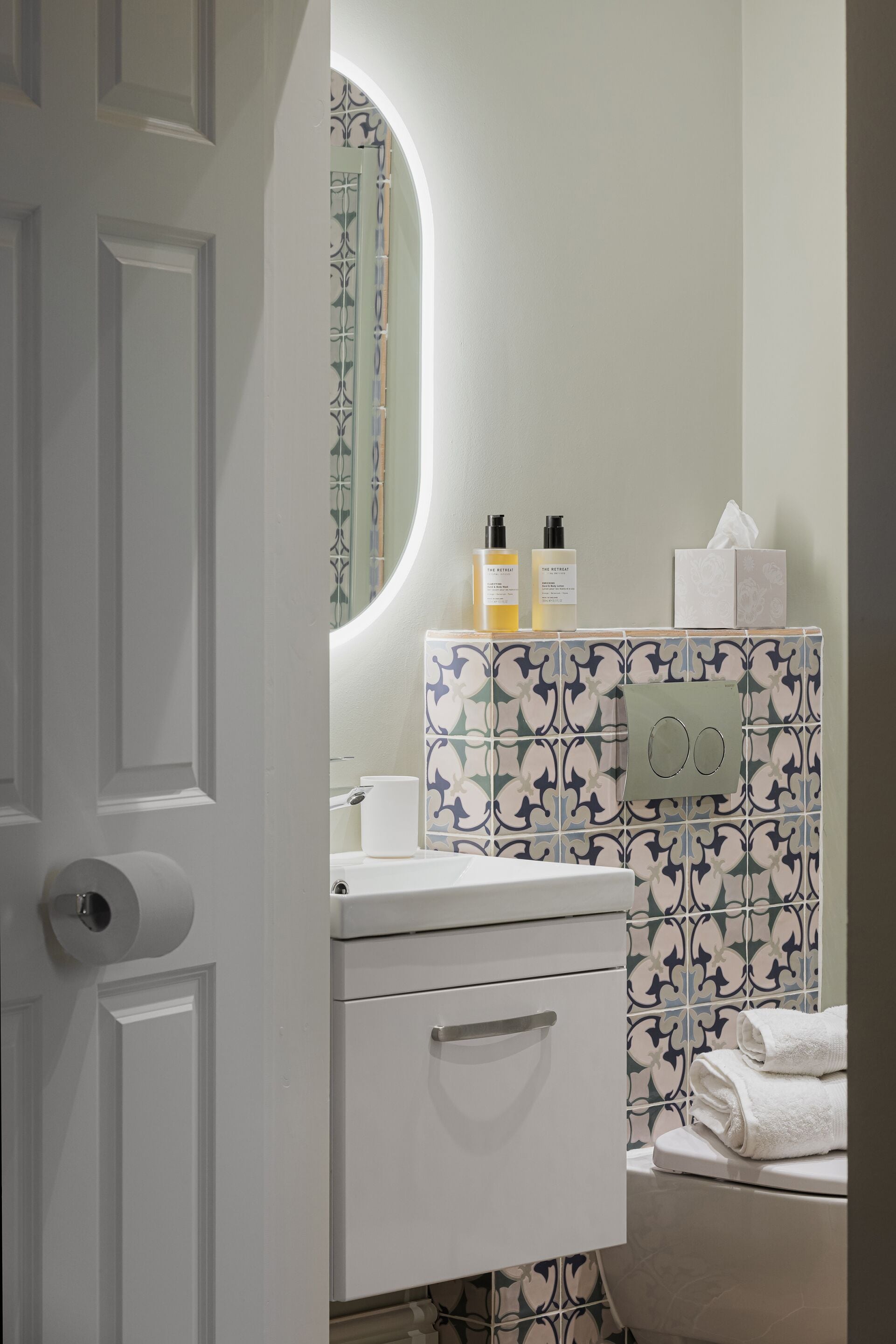 Un baño con inodoro, lavabo, espejo y toallero.