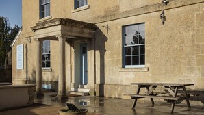 A stone building with a classical entrance, a wooden picnic table, and a planter. - King William Pub with Rooms (Bath)