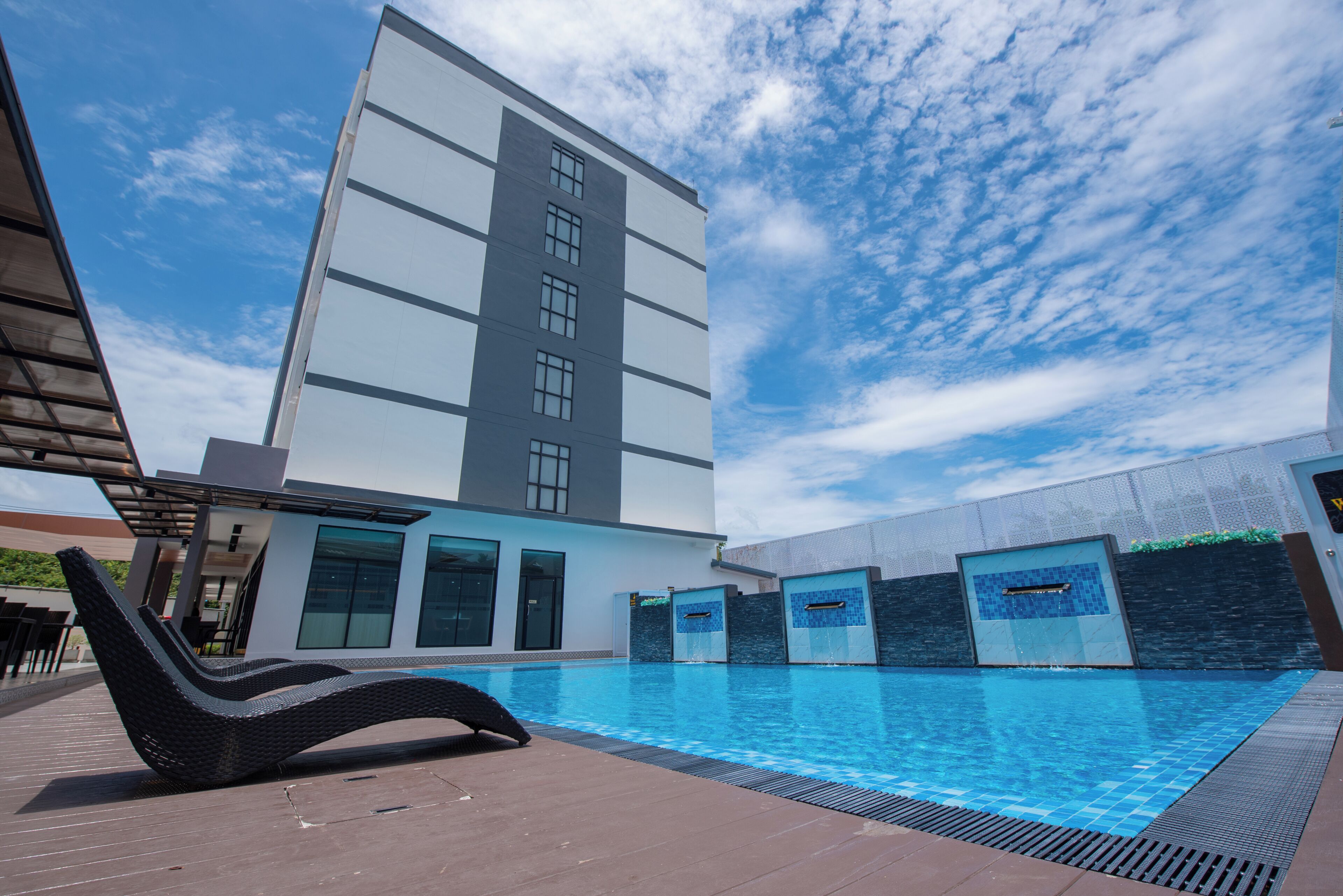 Un bâtiment moderne doté d’une piscine, d’un espace extérieur aménagé et offrant une vue sur un ciel dégagé.
