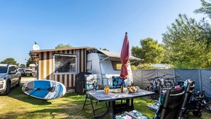 Ein Campingplatz mit Tisch, Stühlen, einem Grillunterstand und einem Zelt.