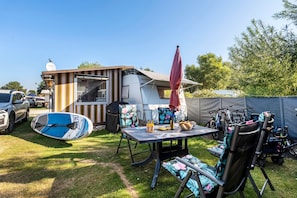 Un càmping amb taula, cadires, una barbacoa coberta i una tenda.