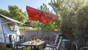 Un camping con una mesa, sillas, un paraguas rojo y bicicletas.
