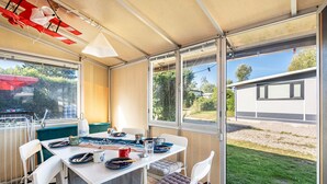 Un espacio de comedor al aire libre techado con una mesa para dos, sillas y vista al jardín.