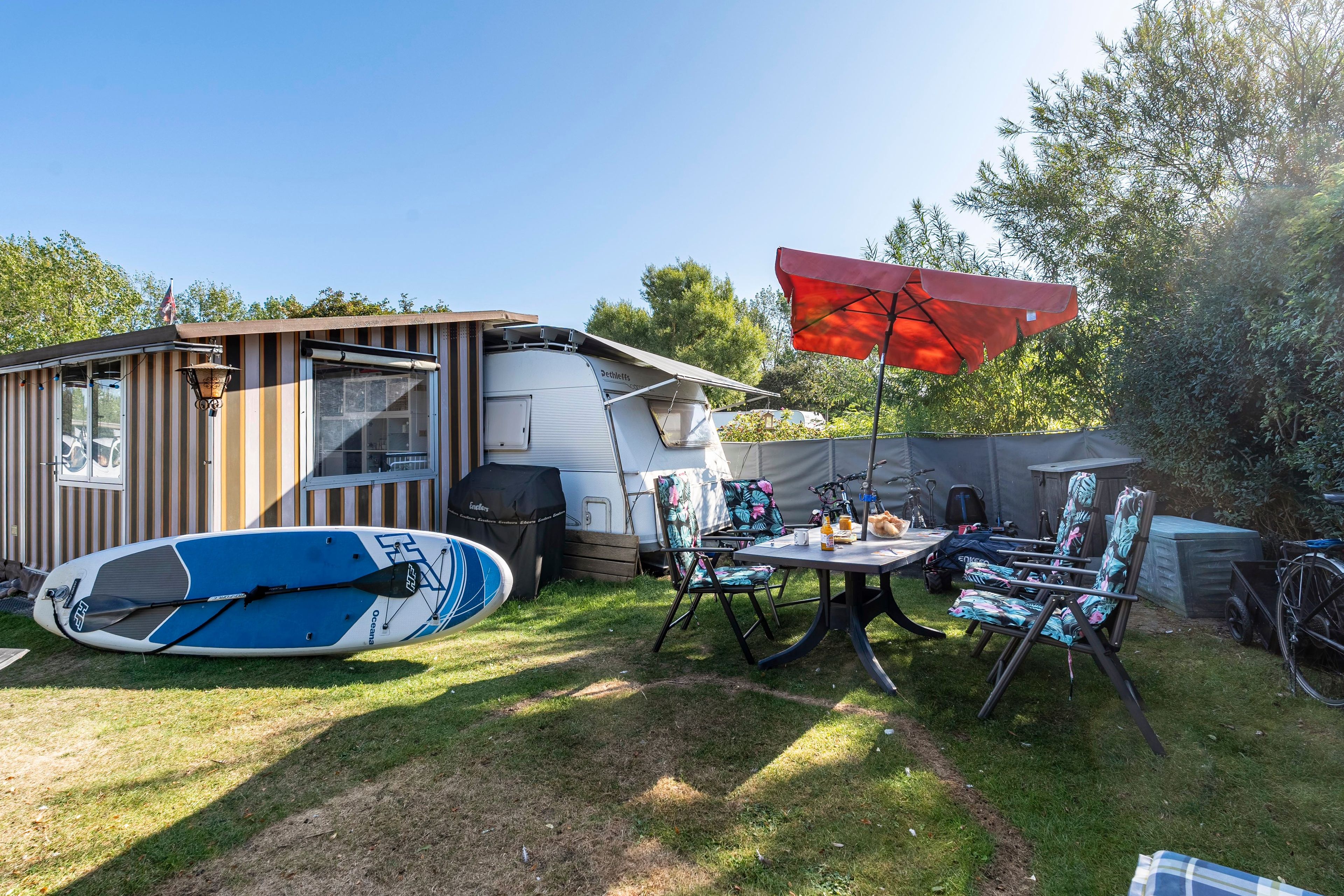 Un terrain de camping doté d’un espace de restauration couvert, d’un kayak et d’une tente.