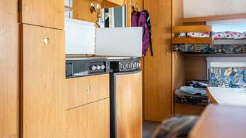A compact kitchenette with a stove, oven, and a small refrigerator.