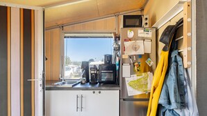 Eine kompakte Küche mit Kühlschrank, Kaffeemaschine und einem Fenster mit Blick ins Freie.