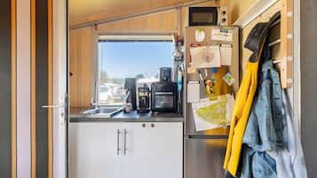 A compact kitchen with a refrigerator, coffee maker, and a window with a view of the outside.