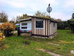 Ein Wohnmobil mit Satellitenschüssel, einer kleinen Veranda und einem Garten.