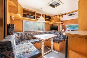 A compact RV interior with a sofa, a small table, and a television.
