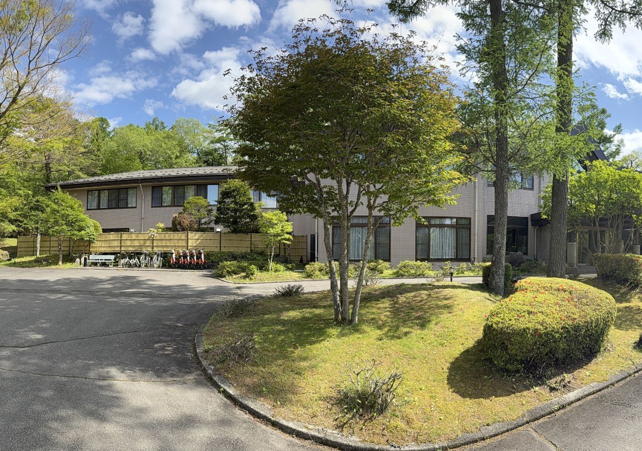 A building with a parking lot, a tree, and a well-maintained lawn.