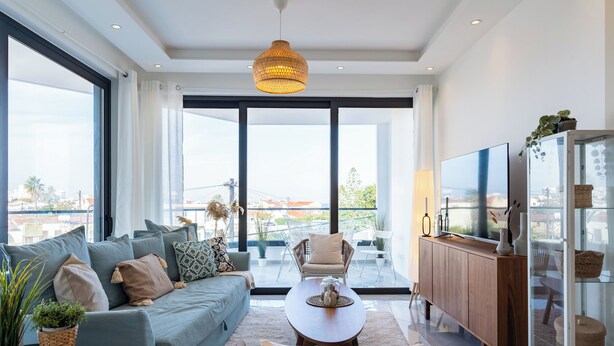 Ein modernes Wohnzimmer mit einer Couch, Sesseln, einem Couchtisch und einem Fernseher.