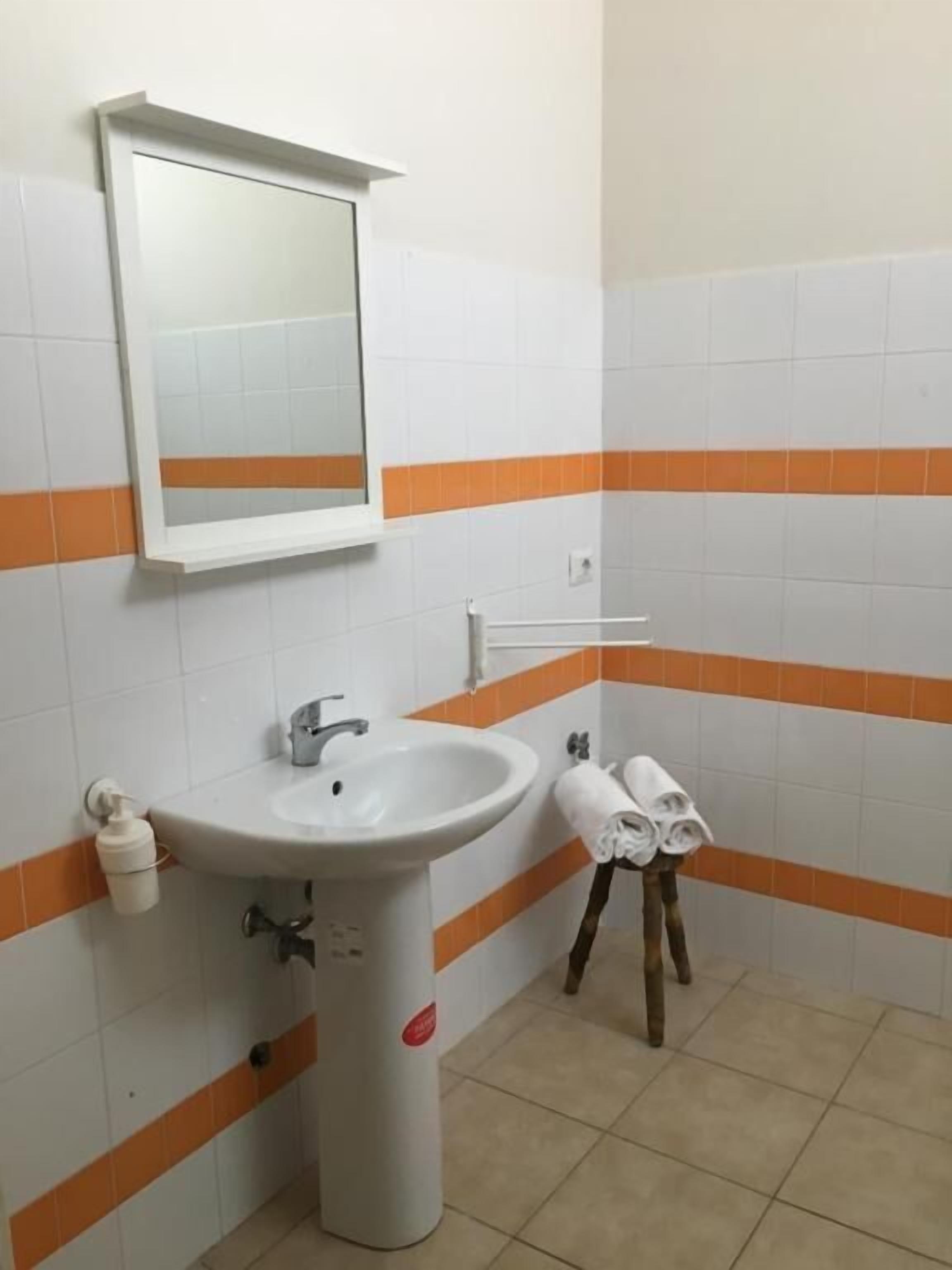 Een badkamer met een wastafel, spiegel en handdoekrek.