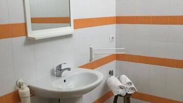 Een badkamer met een wastafel, spiegel en handdoekrek.