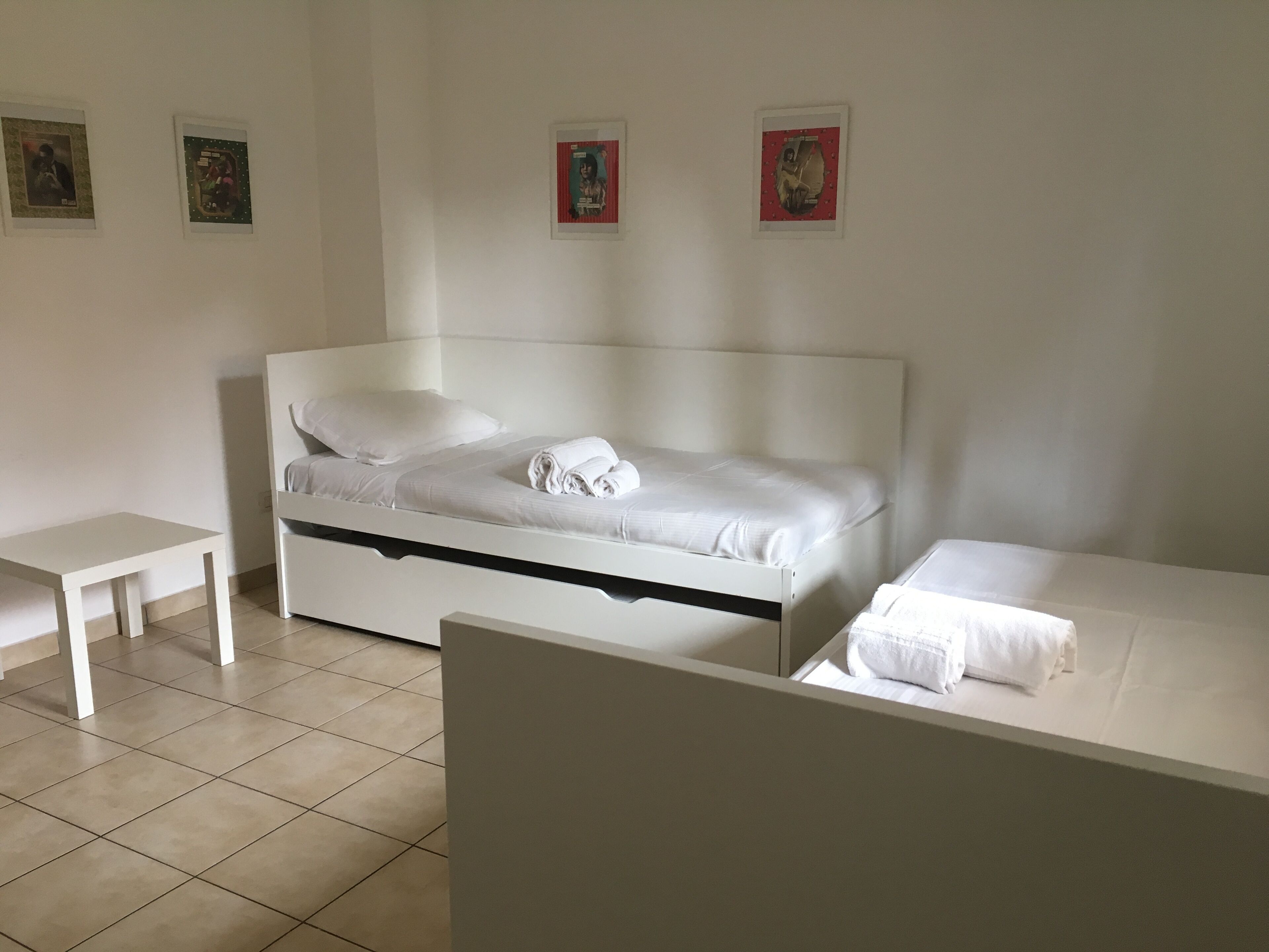A minimalist bedroom with a single bed, a bedside table, and a small table.