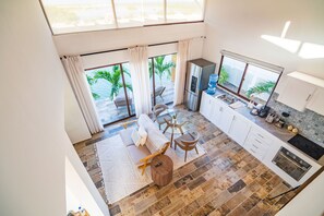 A modern kitchen with a large island, a dining area with a sofa and chairs, and a view of the ocean through large windows. - Ensuring a Very Comfortable & Memorable Stay! Waterfront Property, Outdoor Pool! (San Pedro)