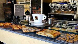Un bancone di pasticceria con dolci, una tazza di caffè e una macchina per l'espresso.