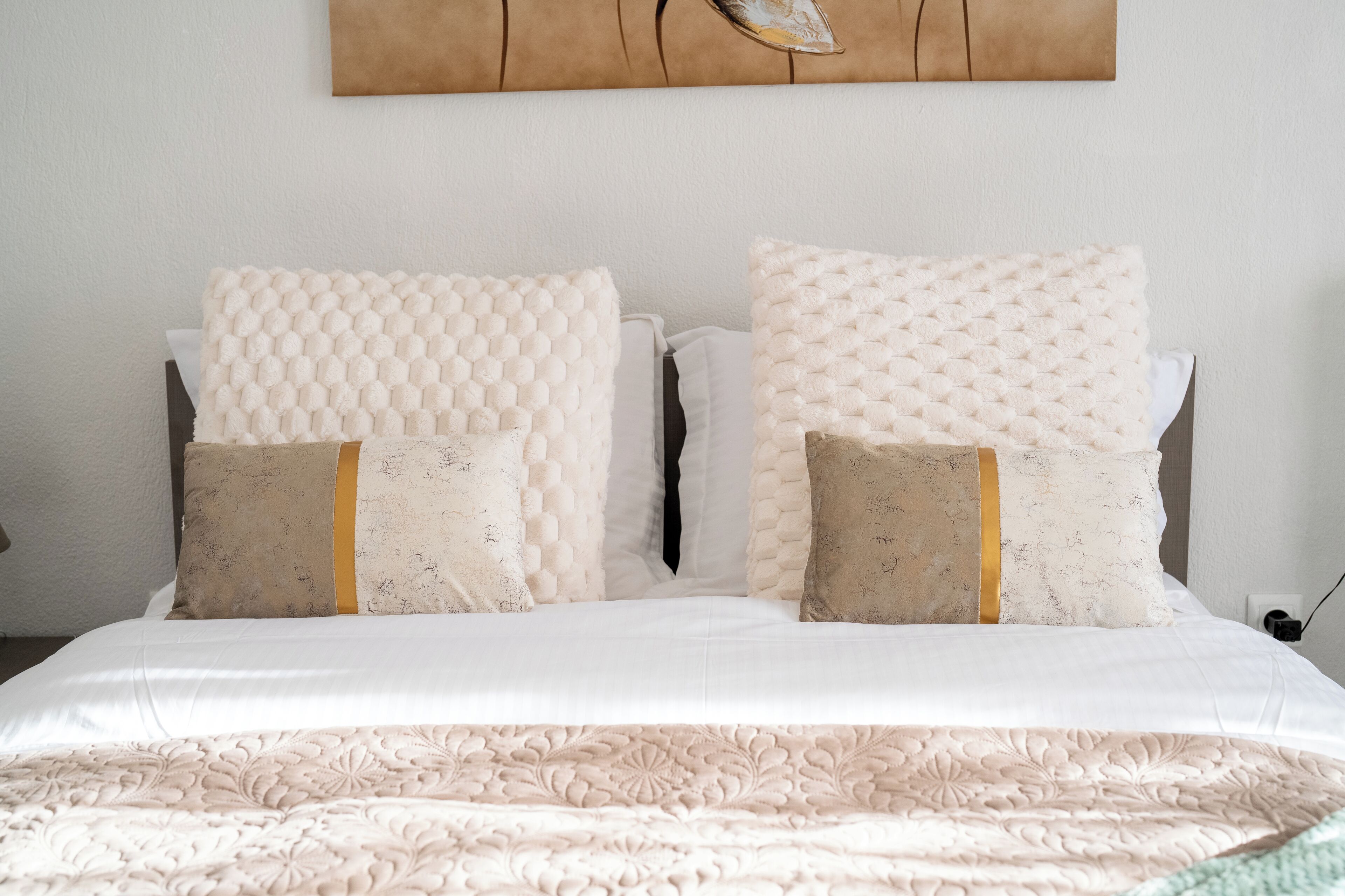 A neatly made bed with a patterned bedspread and two pillows with a textured design.