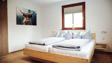 Ein Schlafzimmer mit einem hölzernen Bett, weißer Bettwäsche, einem Fenster mit Jalousien und einem Gemälde eines Stiers an der Wand.