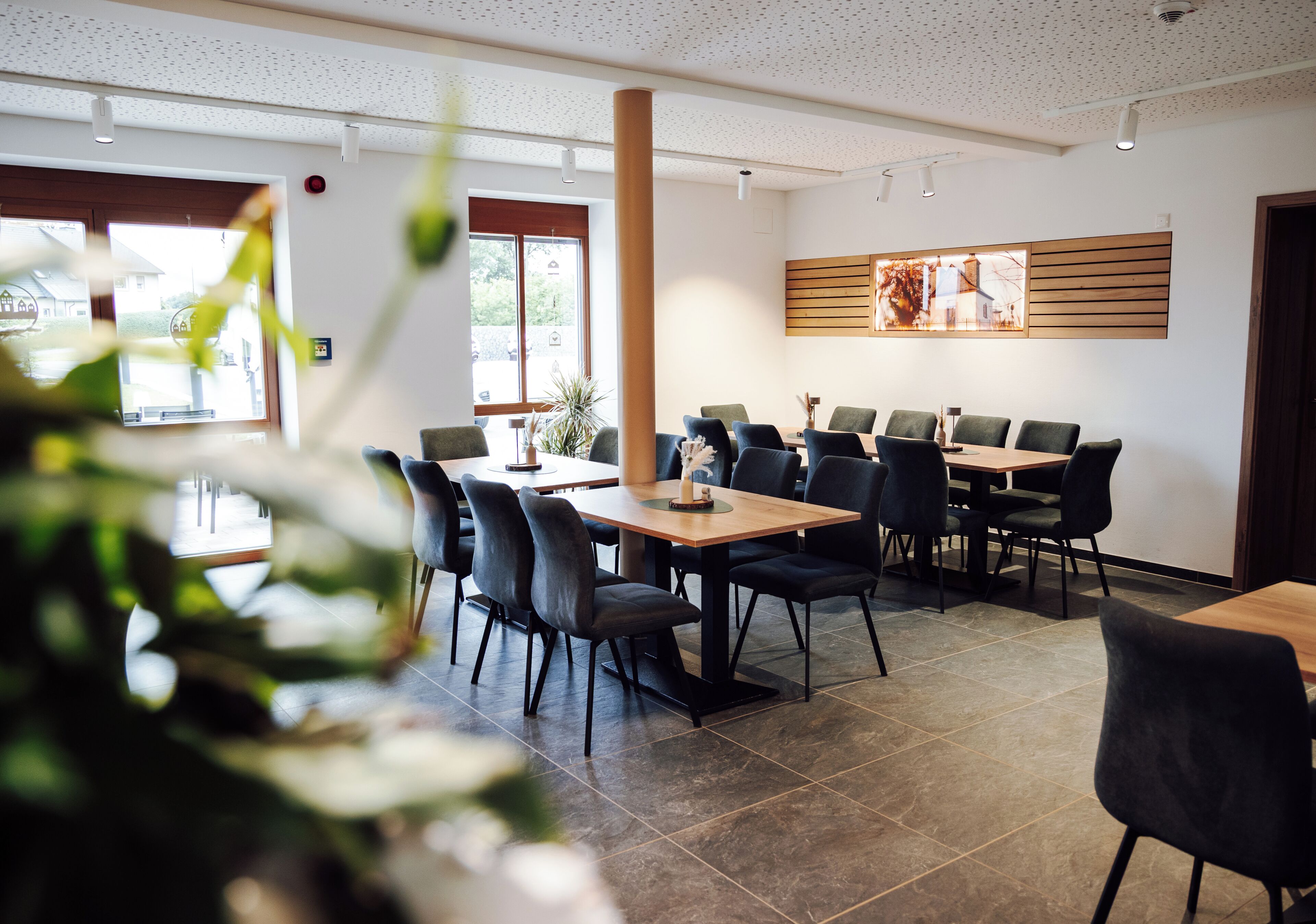 Une salle de conférence avec une longue table et des chaises, un mur décoratif en bois et une vue par la fenêtre.
