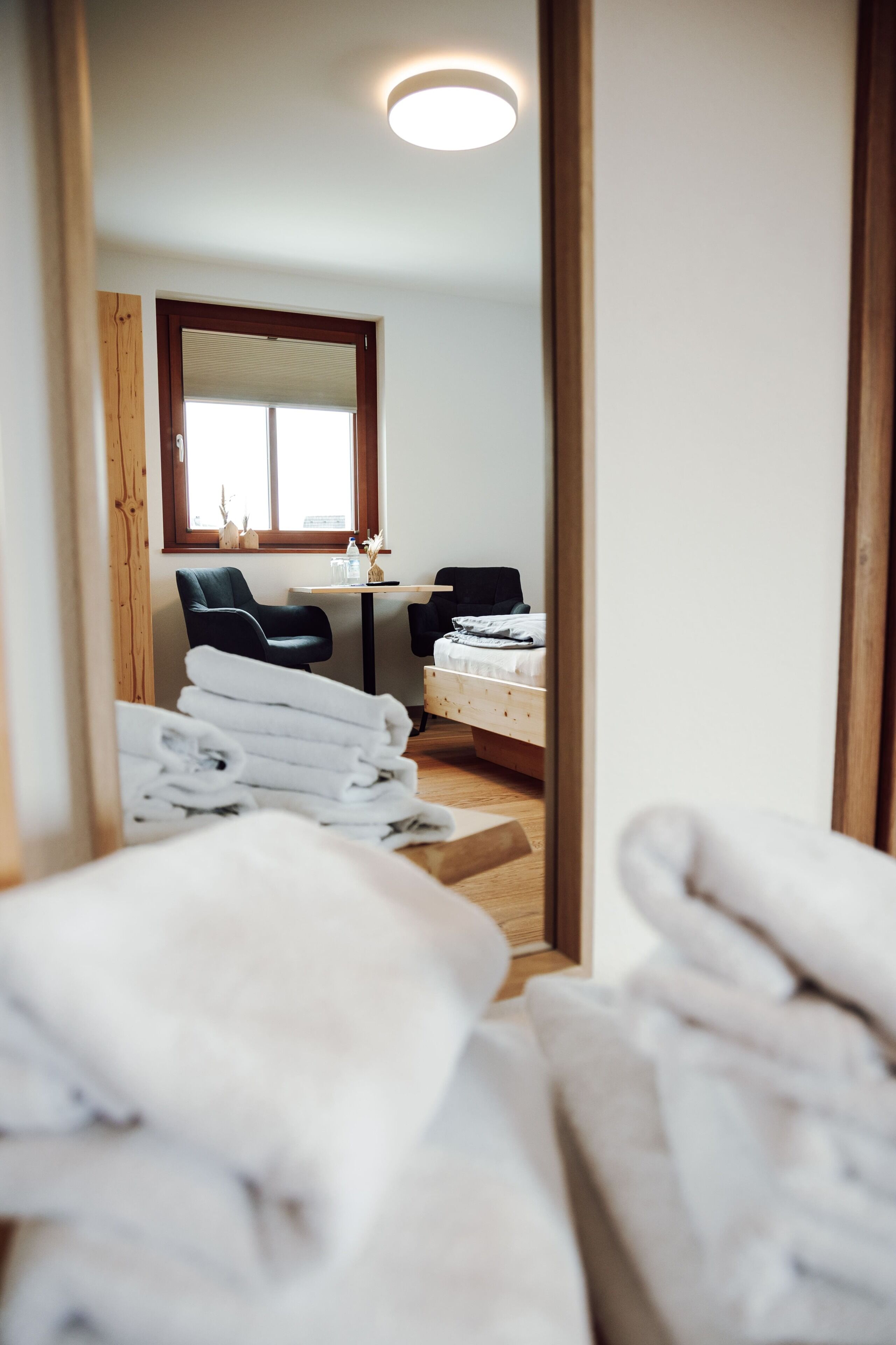 Quarto de hotel com cama, escrivaninha, cadeira e janela.