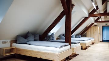 Une pièce avec un plafond en pente, des poutres en bois et deux lits avec des oreillers.