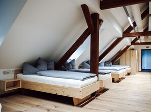 Une pièce avec un plafond en pente, des poutres en bois et deux lits avec des oreillers.