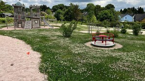 A playground with a slide, climbing structures, and a red circular play area. - Das Fränkische Reichenbach (Reichenbach)