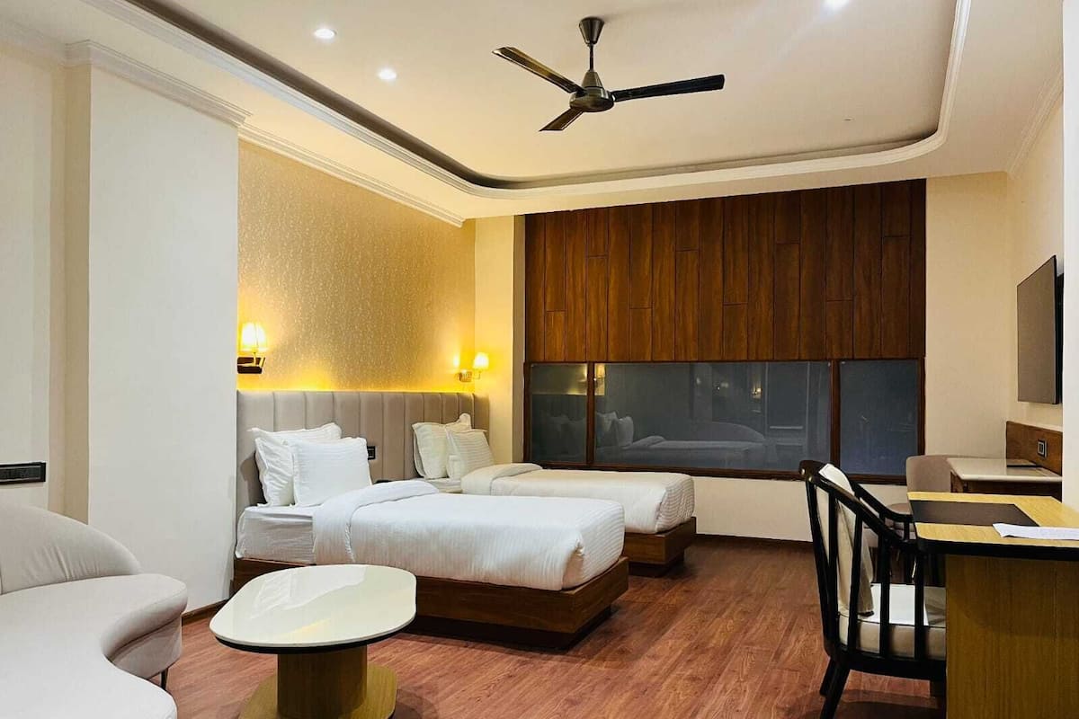 A modern hotel room with a large bed, two bedside tables, a desk, and a chair.