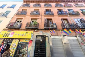 A multi-story building with balconies, a storefront with colorful signage, and rainbow flags. - Cosy 1-bedroom flat in the centre of Madrid Tempory PEL300I (Madrid)