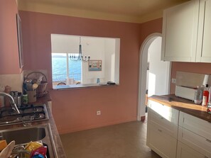 Eine Küche mit Meerblick, einem Chandelier und weißen Schränken.