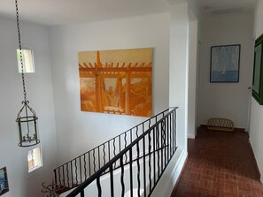 Ein Flur mit Treppe, einer hängenden Laterne und zwei gerahmten Kunstwerken an den Wänden.