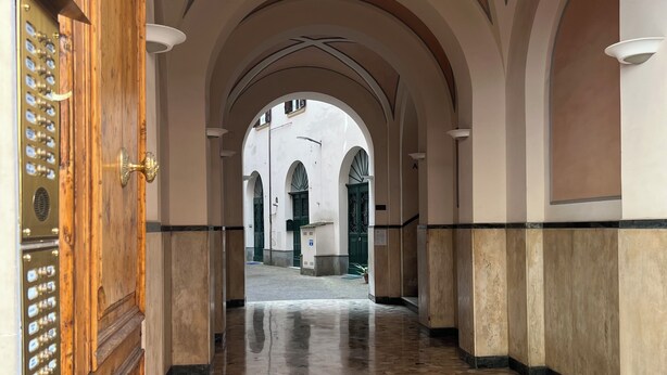 An arched corridor with a tiled floor and a wooden door with a brass handle. - Penthouse23 Vatican Charming Apartment (Roma)