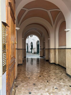 An arched corridor with a tiled floor and a wooden door with a brass handle. - Penthouse23 Vatican Charming Apartment (Roma)