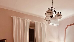 A living room with a round dining table, clear chairs, a green sofa, and a chandelier. - Penthouse23 Vatican Charming Apartment (Roma)