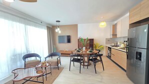 Cozinha moderna com geladeira embutida, armários de madeira e área de refeições com mesa e cadeiras redondas.