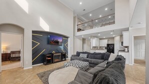 A spacious living area with a fireplace, a sofa set, and a kitchen in the background.