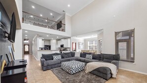 A spacious living area with a gray sectional sofa, a patterned rug, and a flat-screen TV.