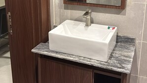 A bathroom with a white sink, a wooden cabinet, and a mirror above it. - Moz One Executive Guest Rooms-Amorè (Lagos)