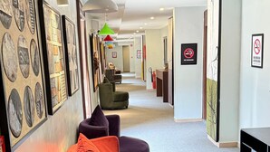 A modern lobby with a curved seating area, framed artwork on the walls, and a no-smoking sign. - Moz One Executive Guest Rooms-Amorè (Lagos)