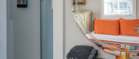 A bathroom with a mirror, a towel rack with a towel labeled "Makeup," and a bottle of lotion on a table.