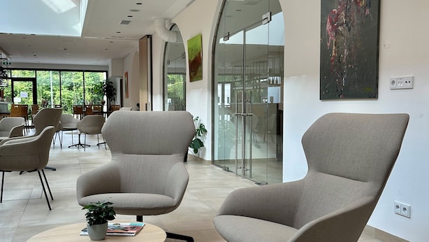 Um interior moderno com duas poltronas, uma mesinha redonda e um quadro abstrato grande na parede.