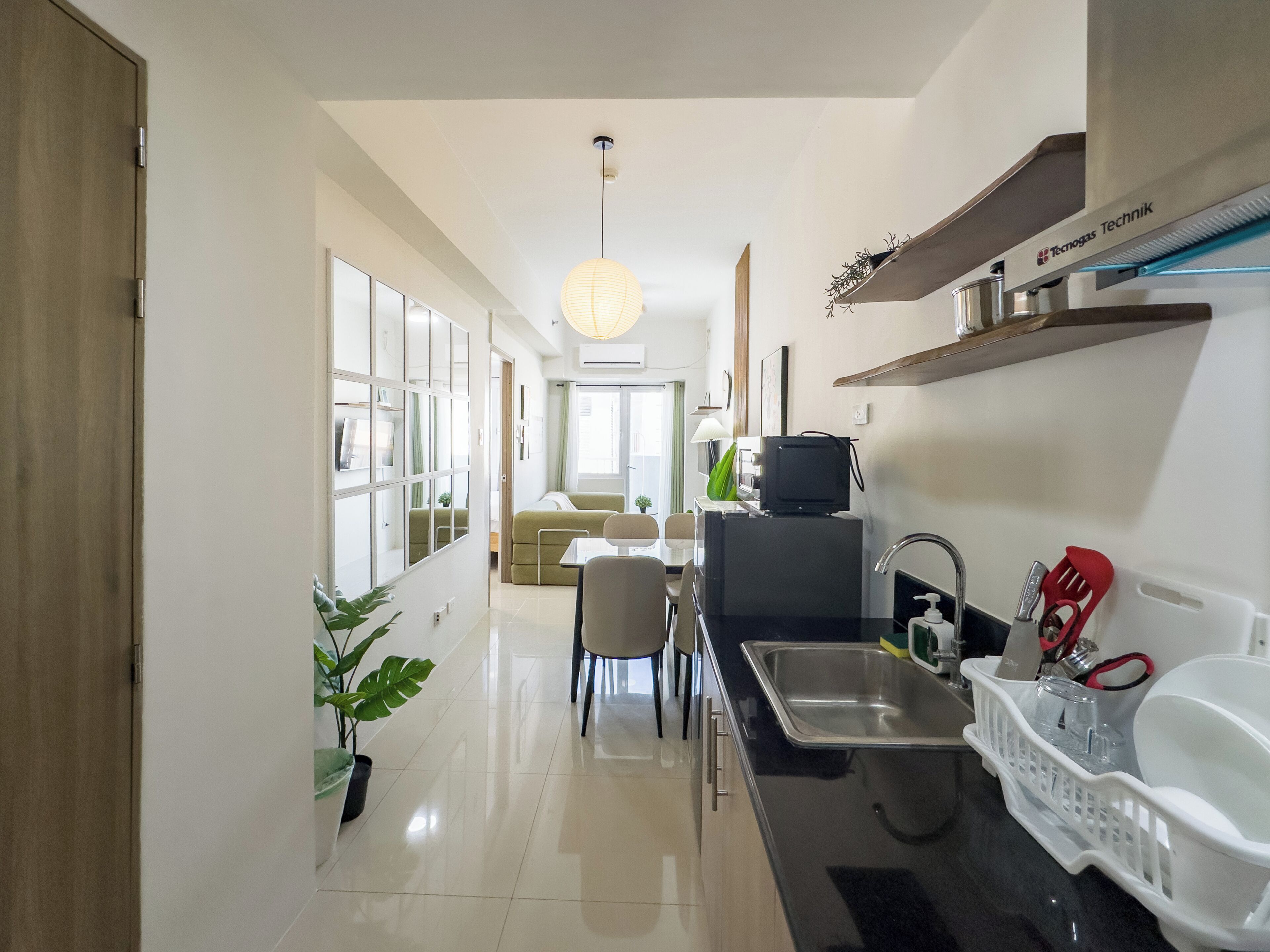 Una cocina moderna con lavamanos, refrigerador y comedor con sillas y mesa.